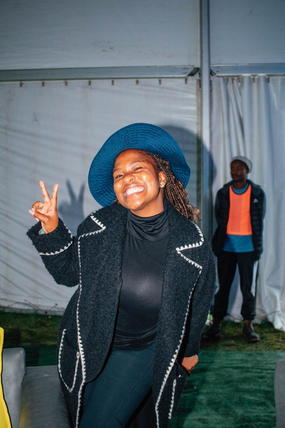 Smiling guest in a blue hat flashing a peace sign inside the tent
