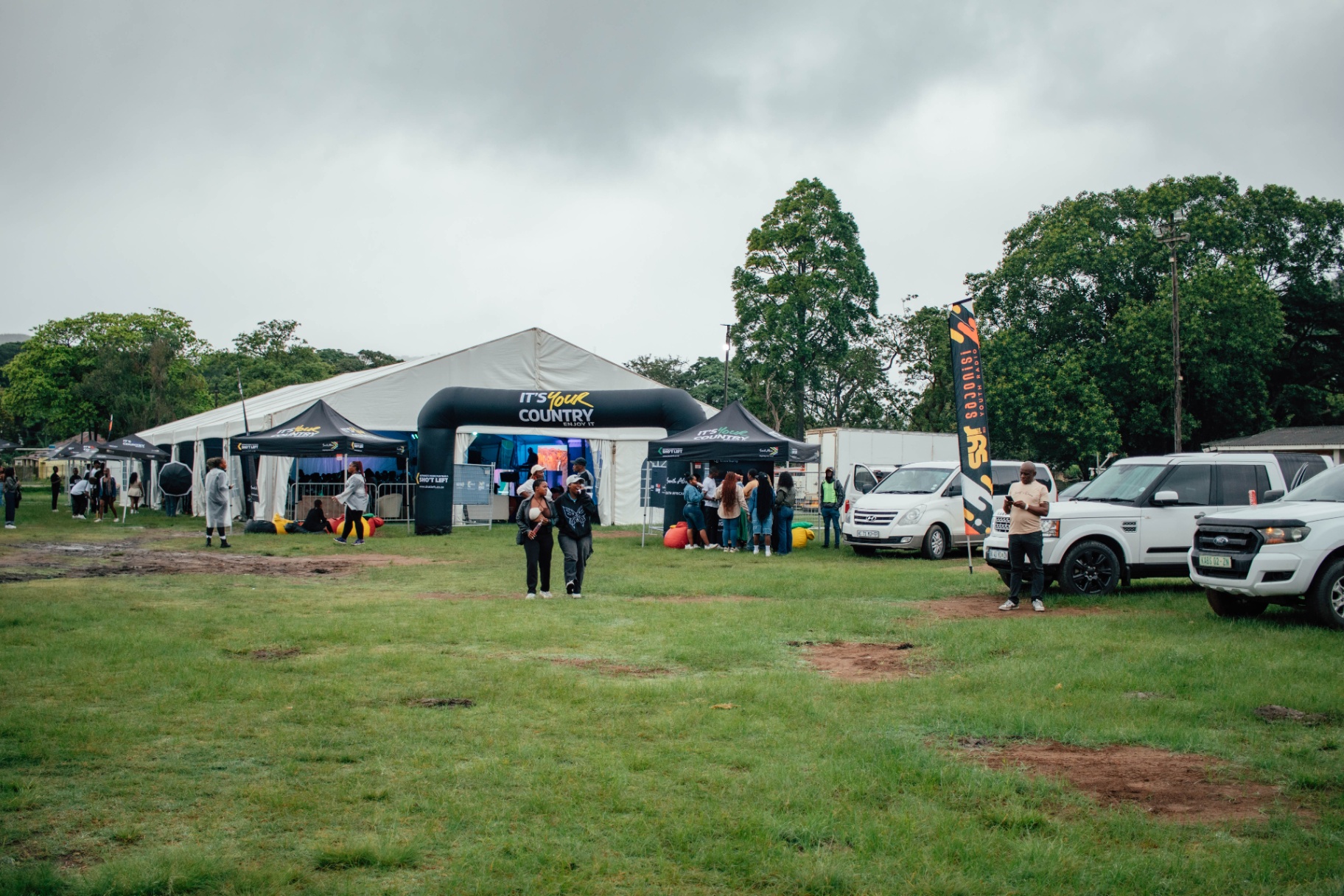 Wide shot of the festival grounds with tents and vehicles