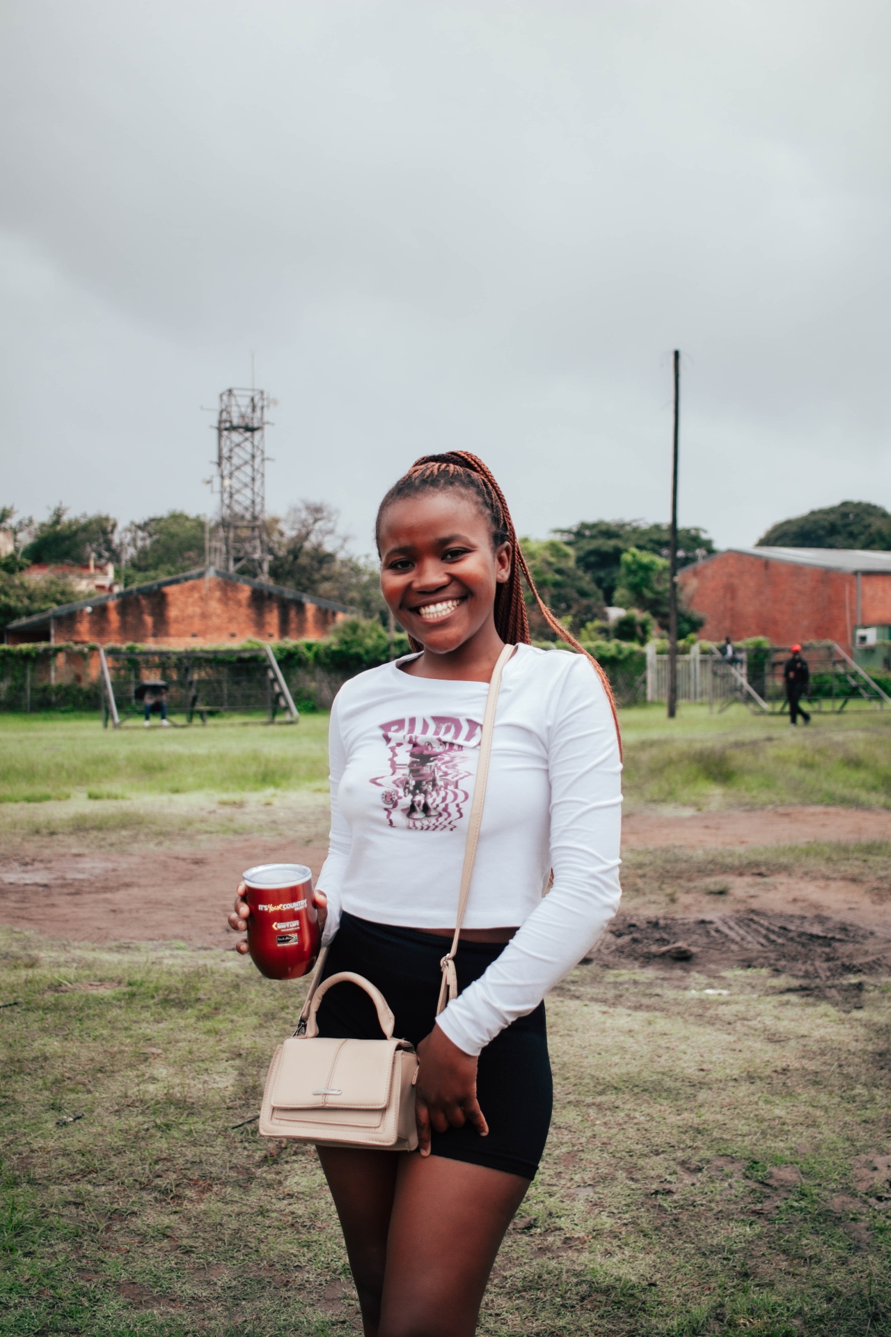 Festival-goer smiling with branded cup on the open field