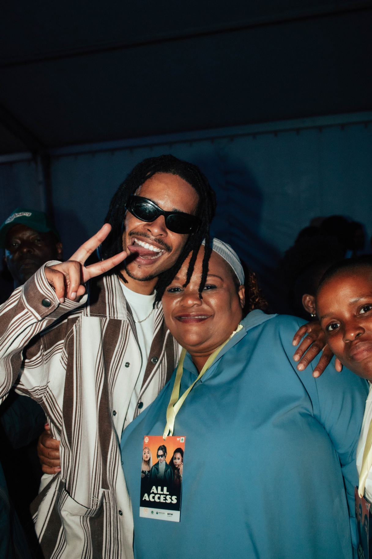 Artist posing with fans flashing peace sign and all-access pass