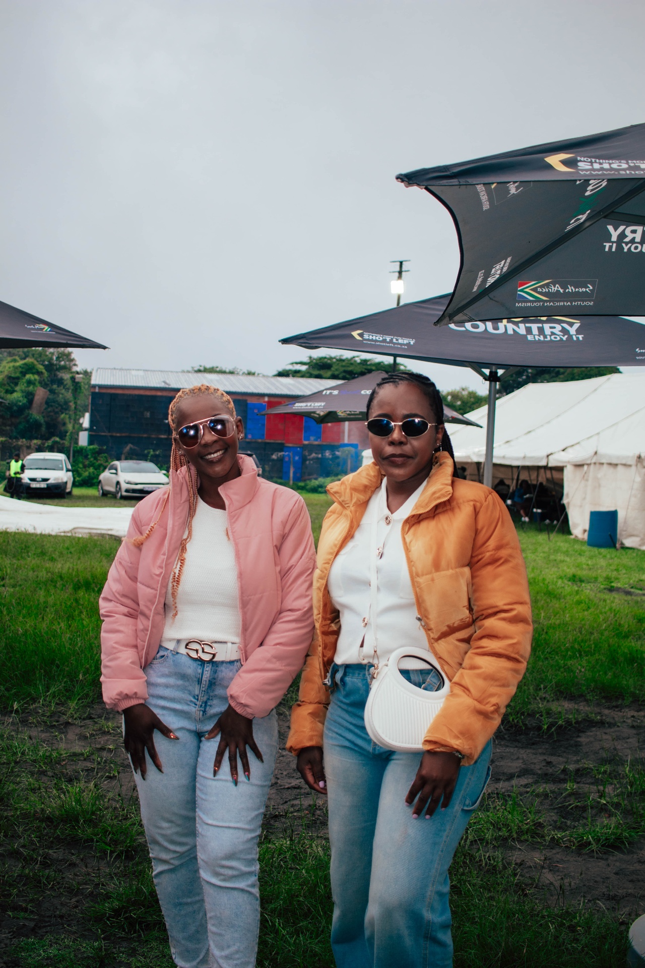 Two friends in puffer jackets under Sho't Left umbrellas